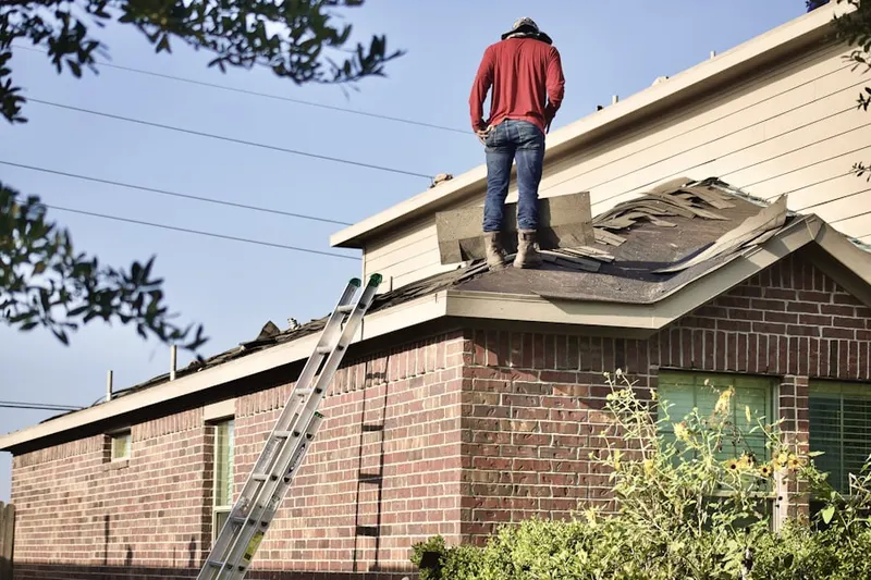 Professional roofer working on a residential roof in Harvest
